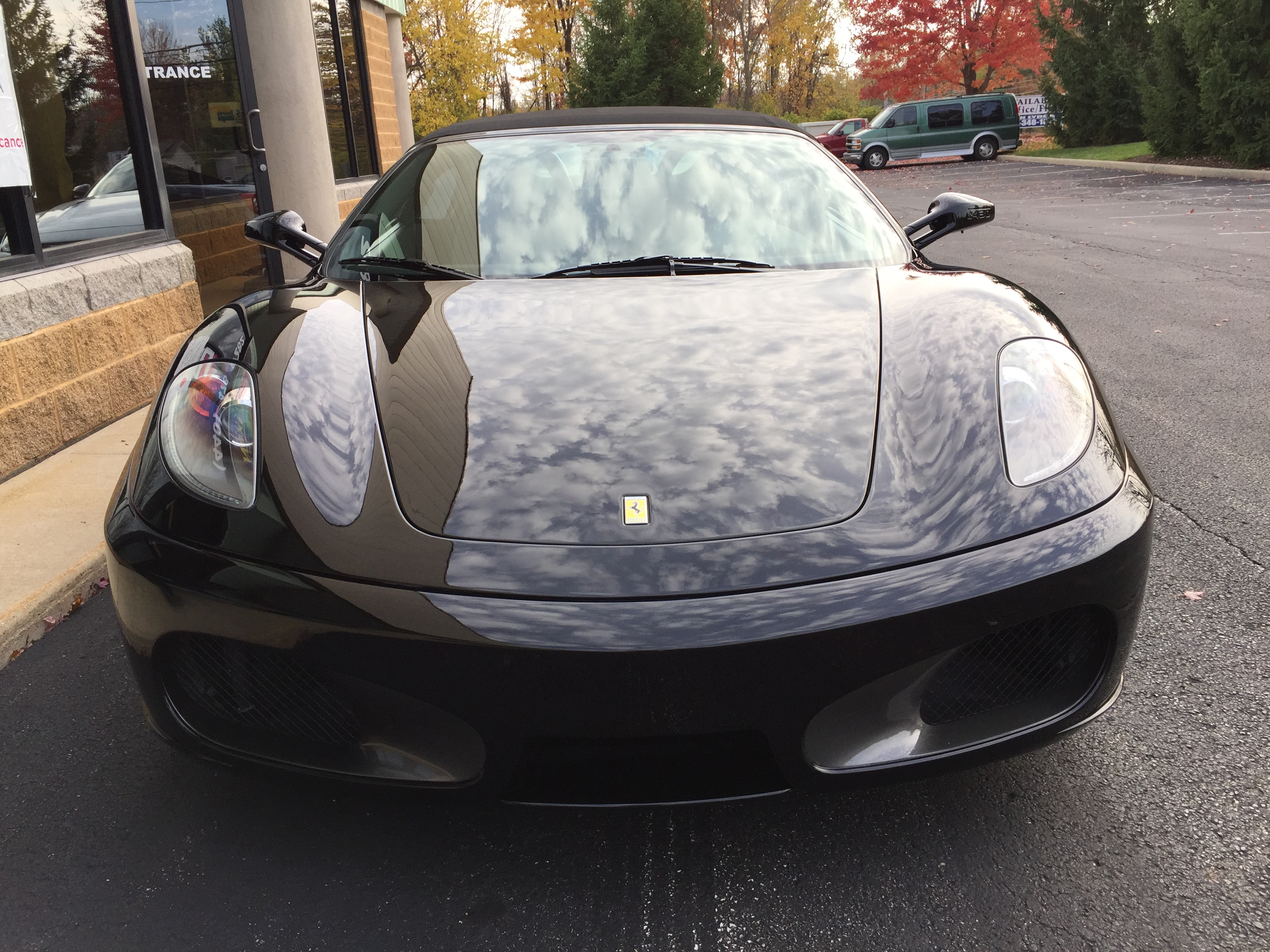 Ferrari F430 Spider — head-on view with mirror-finish hood reflecting clouds